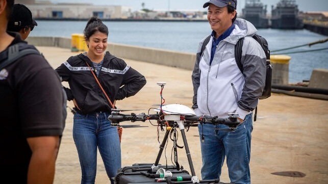 A woman and a man standing next to a UAV prior to launch